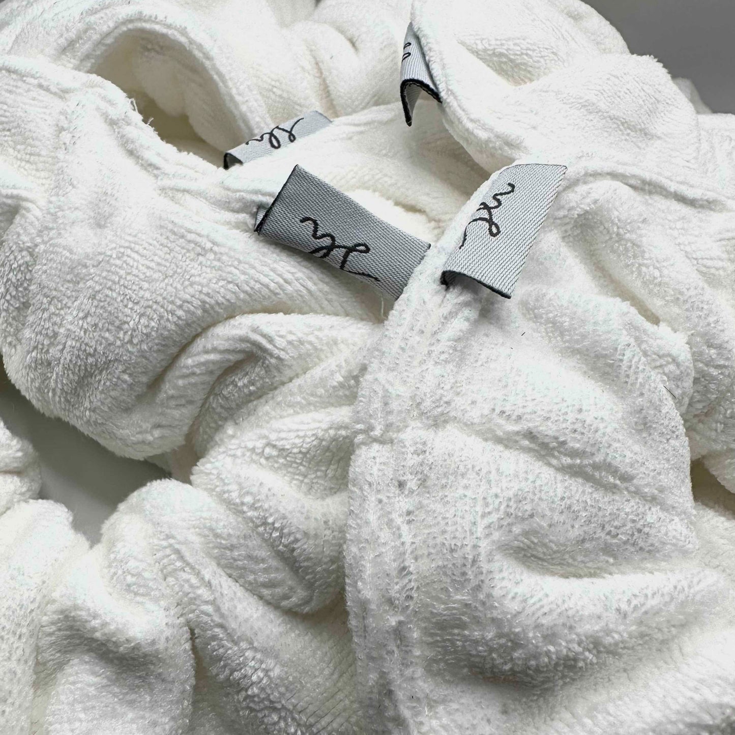 Microfibre towel scrunchie in white. Up close image shot with label in view